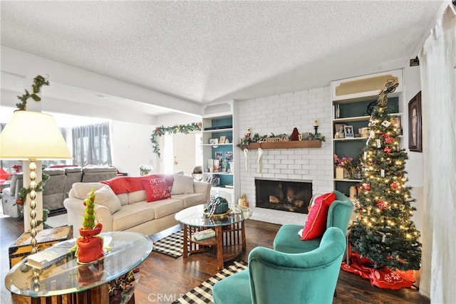 living room with a textured ceiling, a brick fireplace, built in features, and dark wood-type flooring