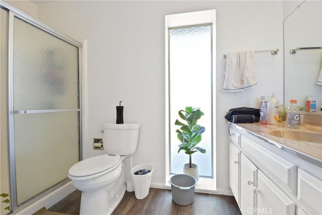 bathroom with toilet, vanity, a shower with door, and hardwood / wood-style flooring