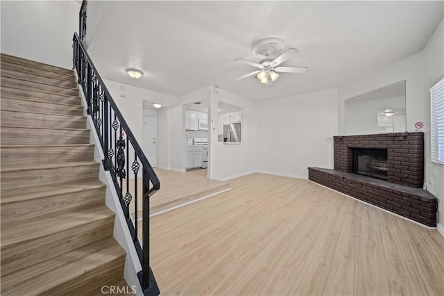 unfurnished living room featuring ceiling fan, a fireplace, and light hardwood / wood-style flooring