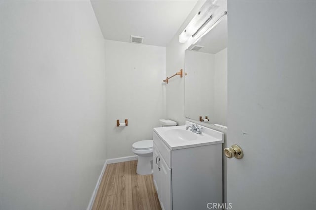 bathroom featuring toilet, vanity, and wood-type flooring