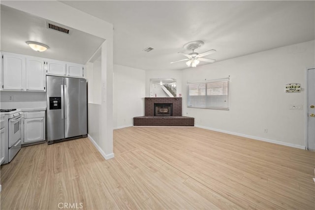 kitchen featuring white cabinets, a brick fireplace, white stove, stainless steel fridge with ice dispenser, and ceiling fan