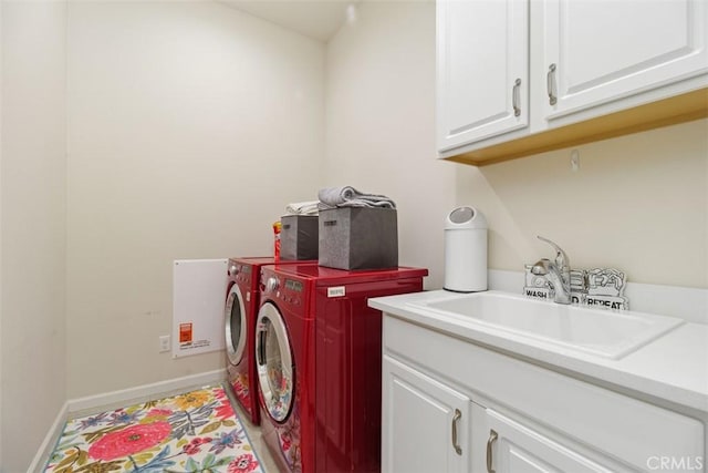 clothes washing area featuring separate washer and dryer, sink, and cabinets