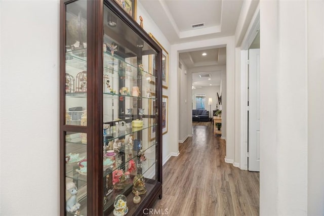 corridor featuring hardwood / wood-style flooring and a raised ceiling