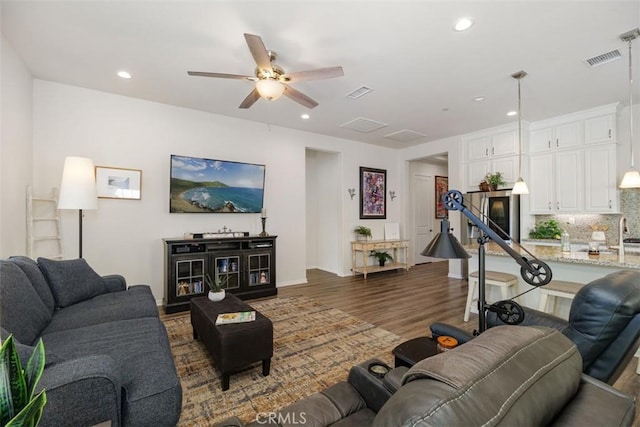 living room featuring ceiling fan and dark wood-type flooring