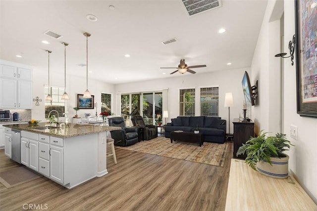 kitchen featuring a center island with sink, white cabinetry, sink, and dark stone counters