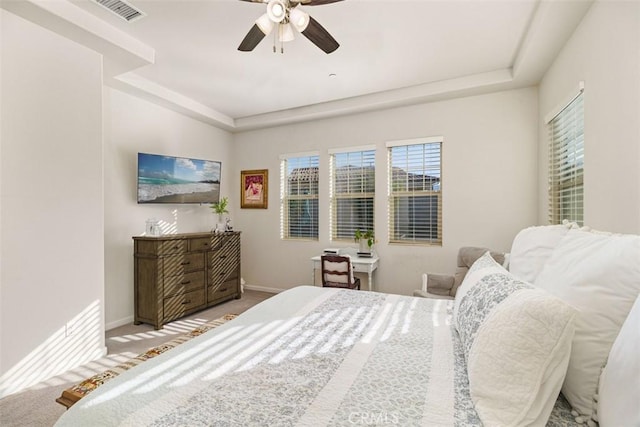 carpeted bedroom with a tray ceiling and ceiling fan