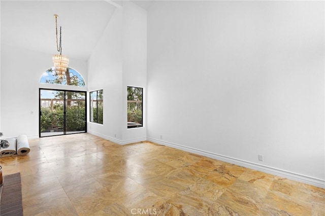 unfurnished living room with an inviting chandelier and a towering ceiling