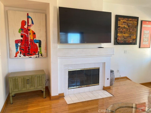 living room with hardwood / wood-style flooring and a tiled fireplace