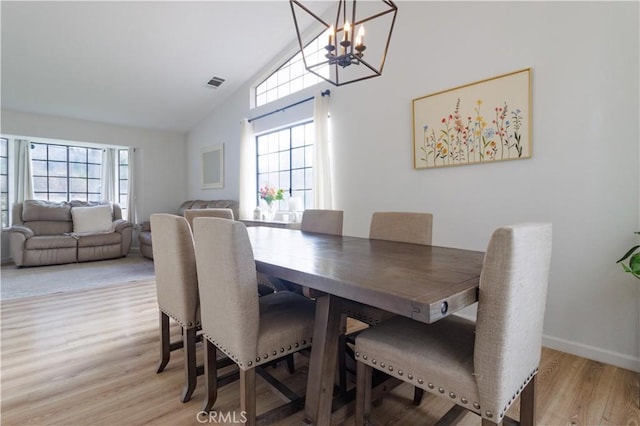 dining room featuring light hardwood / wood-style flooring, lofted ceiling, and an inviting chandelier