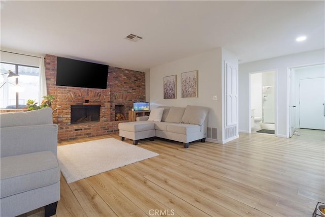 living room featuring a brick fireplace and light hardwood / wood-style flooring