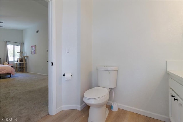 bathroom with toilet, hardwood / wood-style flooring, and vanity