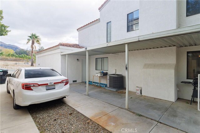 view of property exterior with a mountain view, central AC unit, and a carport