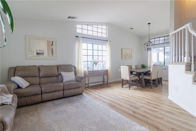 living room featuring vaulted ceiling, a chandelier, and light hardwood / wood-style flooring