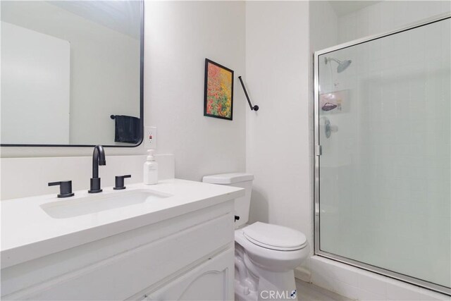 bathroom with toilet, a shower with door, and vanity