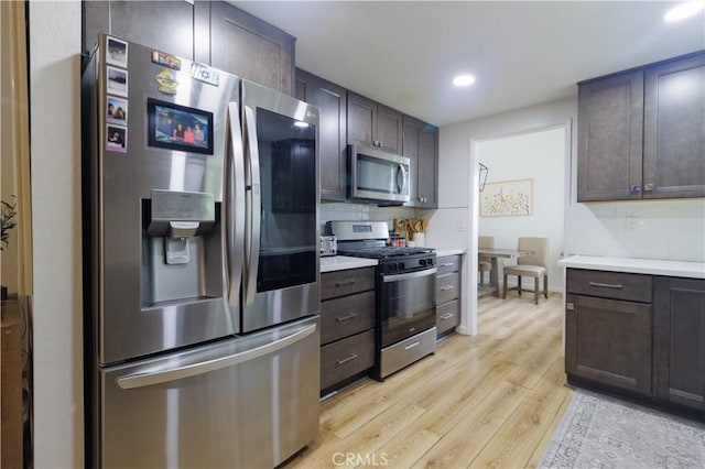 kitchen featuring stainless steel appliances, decorative backsplash, light hardwood / wood-style floors, and dark brown cabinetry