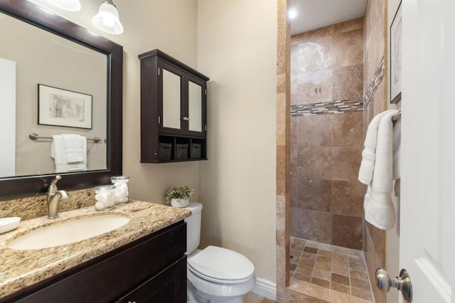 bathroom with toilet, vanity, and a tile shower