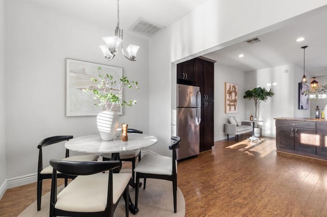 dining space with dark hardwood / wood-style flooring and an inviting chandelier