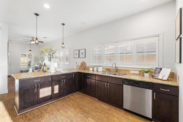 kitchen with dark brown cabinetry, decorative light fixtures, sink, stainless steel dishwasher, and light hardwood / wood-style flooring