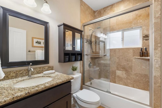 full bathroom featuring toilet, bath / shower combo with glass door, and vanity