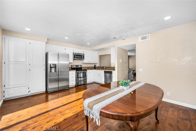 kitchen featuring white cabinets, appliances with stainless steel finishes, and dark hardwood / wood-style floors