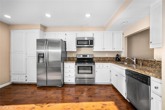 kitchen with dark hardwood / wood-style floors, dark stone countertops, sink, white cabinetry, and appliances with stainless steel finishes