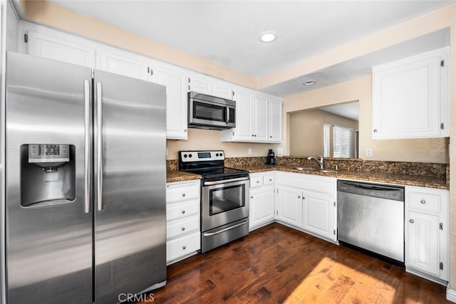 kitchen with sink, dark stone counters, stainless steel appliances, white cabinets, and dark hardwood / wood-style flooring