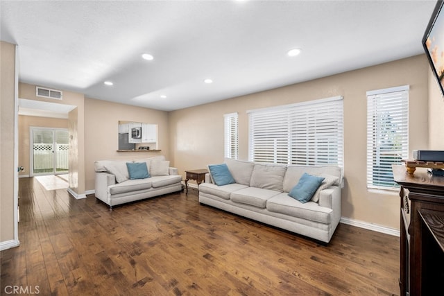 living room with dark wood-type flooring and plenty of natural light