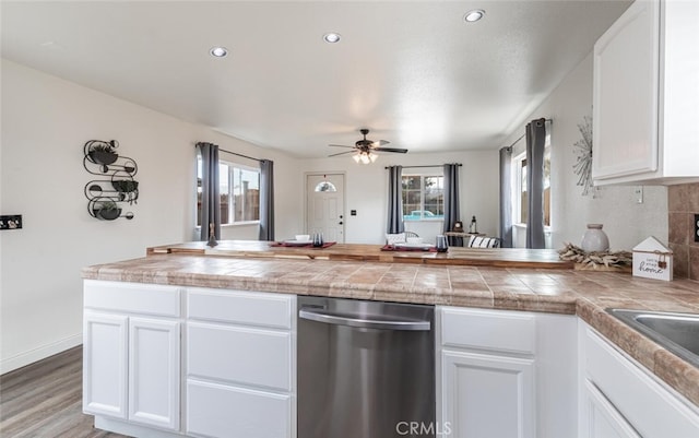 kitchen with white cabinetry, tile countertops, light wood-type flooring, ceiling fan, and stainless steel dishwasher