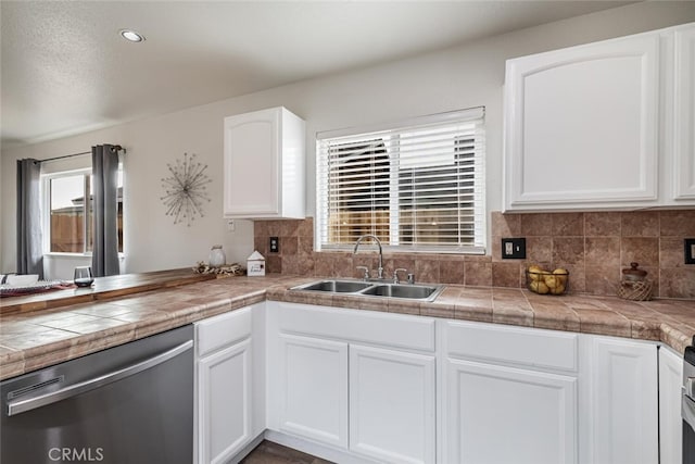 kitchen featuring tasteful backsplash, dishwasher, sink, white cabinetry, and tile counters