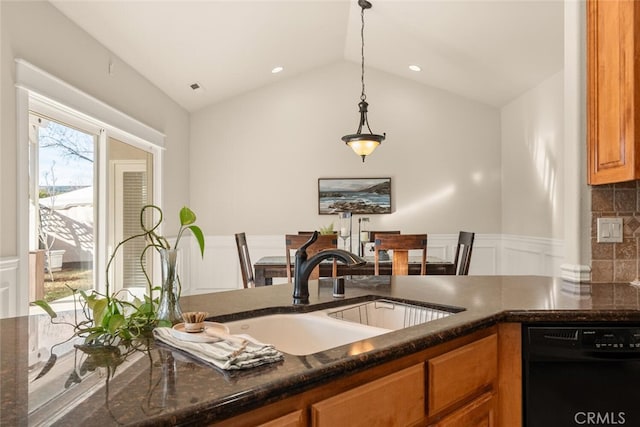 kitchen featuring pendant lighting, lofted ceiling, black dishwasher, dark stone countertops, and sink