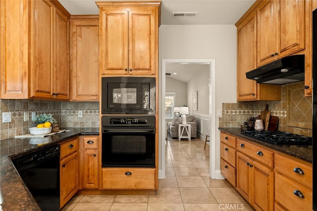 kitchen with light tile patterned floors, dark stone countertops, decorative backsplash, and black appliances