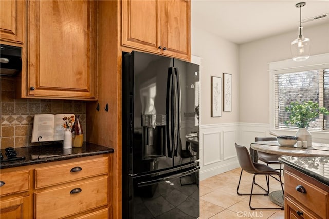 kitchen featuring light tile patterned floors, decorative backsplash, black fridge with ice dispenser, dark stone countertops, and hanging light fixtures