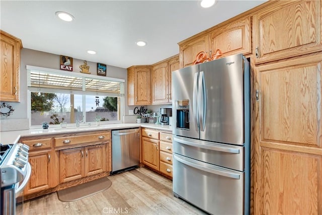 kitchen featuring appliances with stainless steel finishes, sink, and light hardwood / wood-style floors