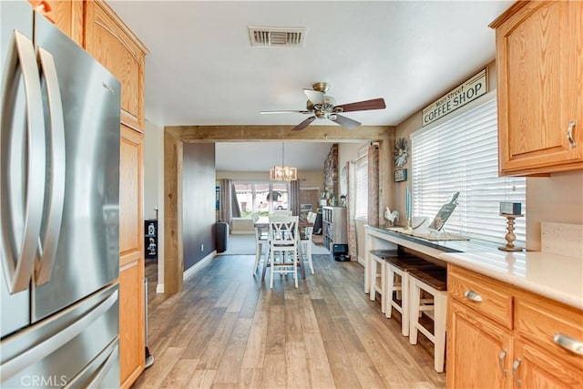 kitchen featuring ceiling fan, hanging light fixtures, light wood-type flooring, and stainless steel refrigerator