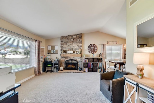 living room with lofted ceiling, a healthy amount of sunlight, a stone fireplace, and carpet flooring