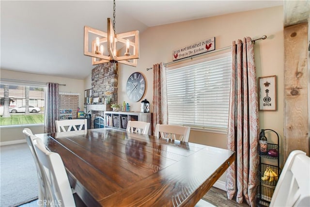 dining area with a chandelier, lofted ceiling, a fireplace, and carpet floors