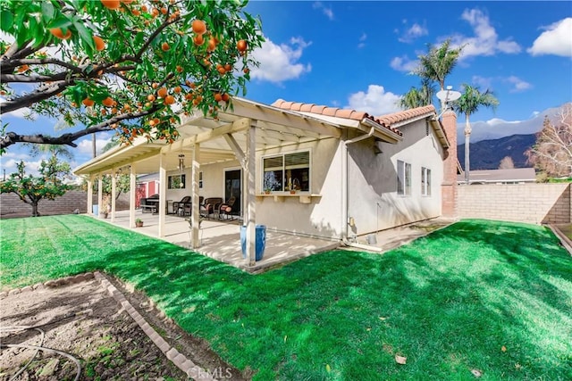 back of house featuring a mountain view, a patio, a lawn, and a pergola