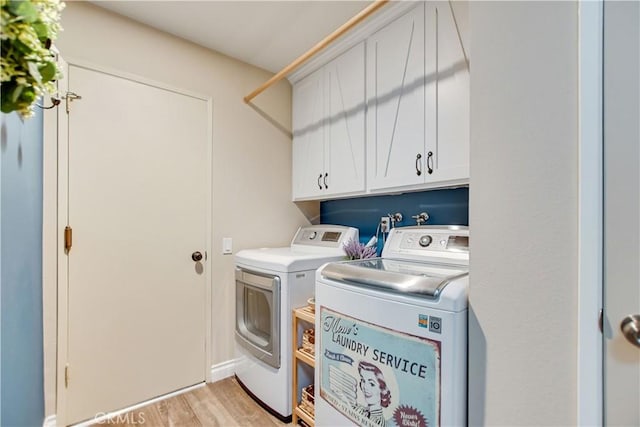 clothes washing area with cabinets, washing machine and dryer, and light wood-type flooring