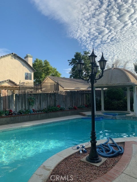 view of swimming pool featuring a gazebo and an in ground hot tub