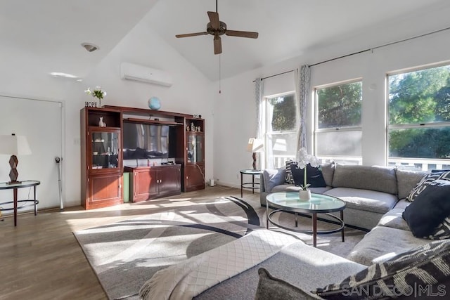 living room with light wood-type flooring, ceiling fan, an AC wall unit, and high vaulted ceiling