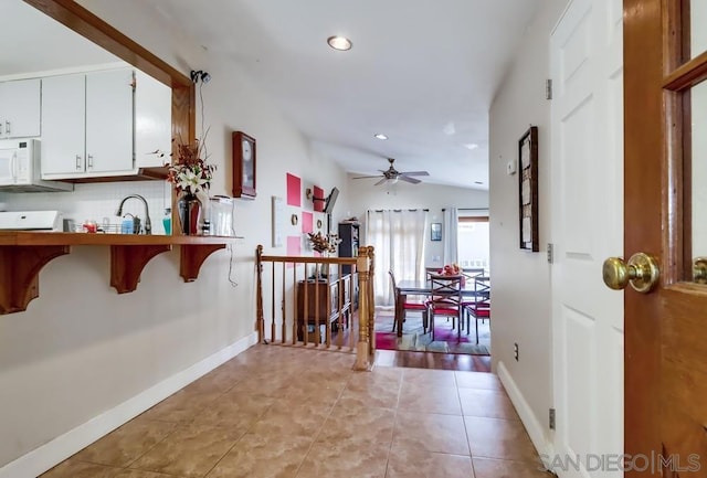 hallway featuring light tile patterned floors, vaulted ceiling, and sink