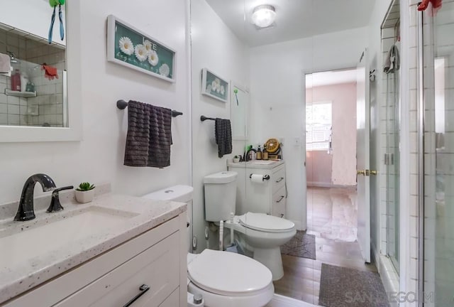 bathroom with tile patterned floors, toilet, vanity, and an enclosed shower