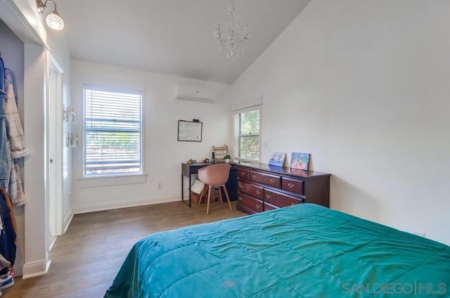 bedroom featuring wood-type flooring, vaulted ceiling, a chandelier, and a wall mounted air conditioner