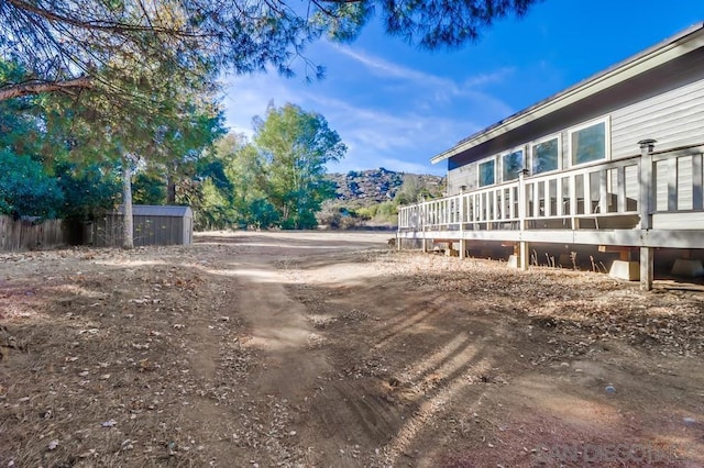 view of yard featuring a storage shed and a deck with mountain view