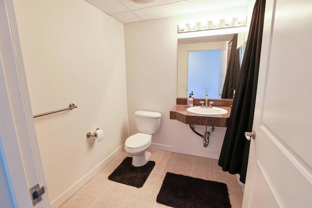 bathroom with toilet, tile patterned floors, a drop ceiling, and sink