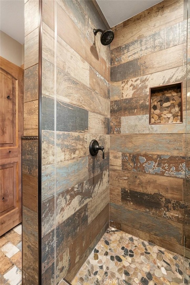 full bathroom featuring stone finish flooring and tiled shower