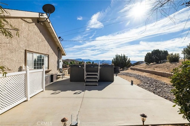 view of patio with a mountain view and a hot tub