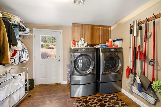 clothes washing area featuring dark wood-type flooring, cabinet space, visible vents, and washer and clothes dryer