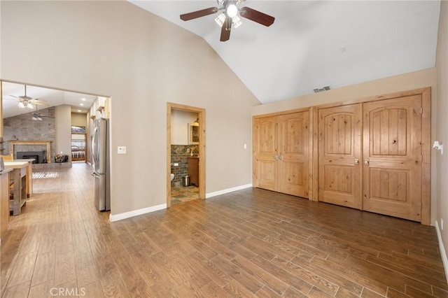 bedroom with visible vents, a fireplace, freestanding refrigerator, and wood finished floors