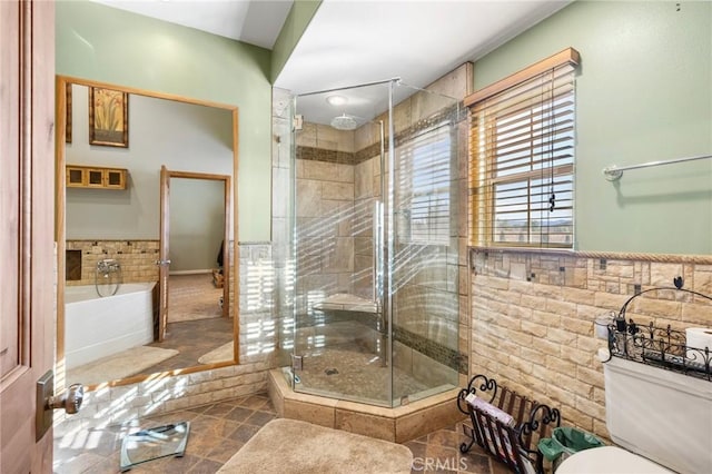 bathroom featuring a wainscoted wall, a stall shower, tile patterned flooring, tile walls, and a bath